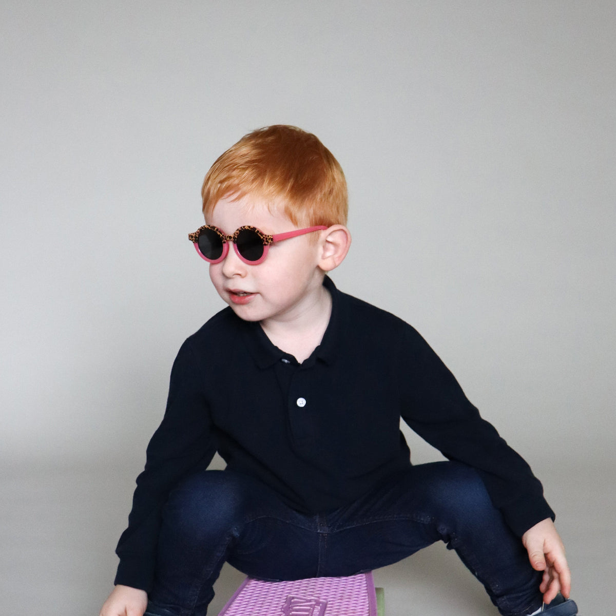 Paire de lunettes de soleil bébé catégorie 4, monture en TPEE effet transparent couleur rose avec motif léopard sur le haut. Mise en situation portée de profil