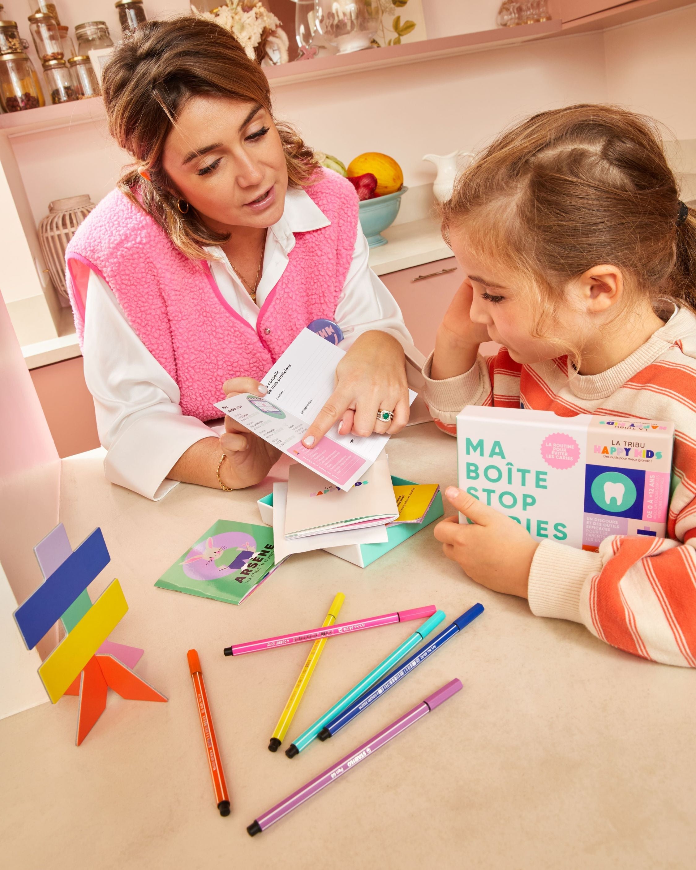 Maman qui montre Ma Boîte Stop Caries a une enfant